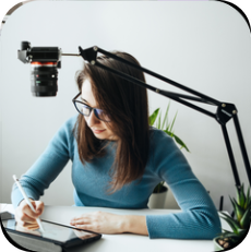 A content creator sketching on a tablet beside her camera
