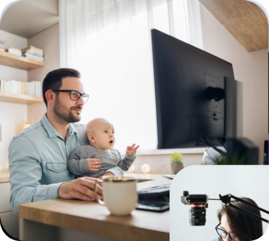 A father working at his desk while holding his baby
